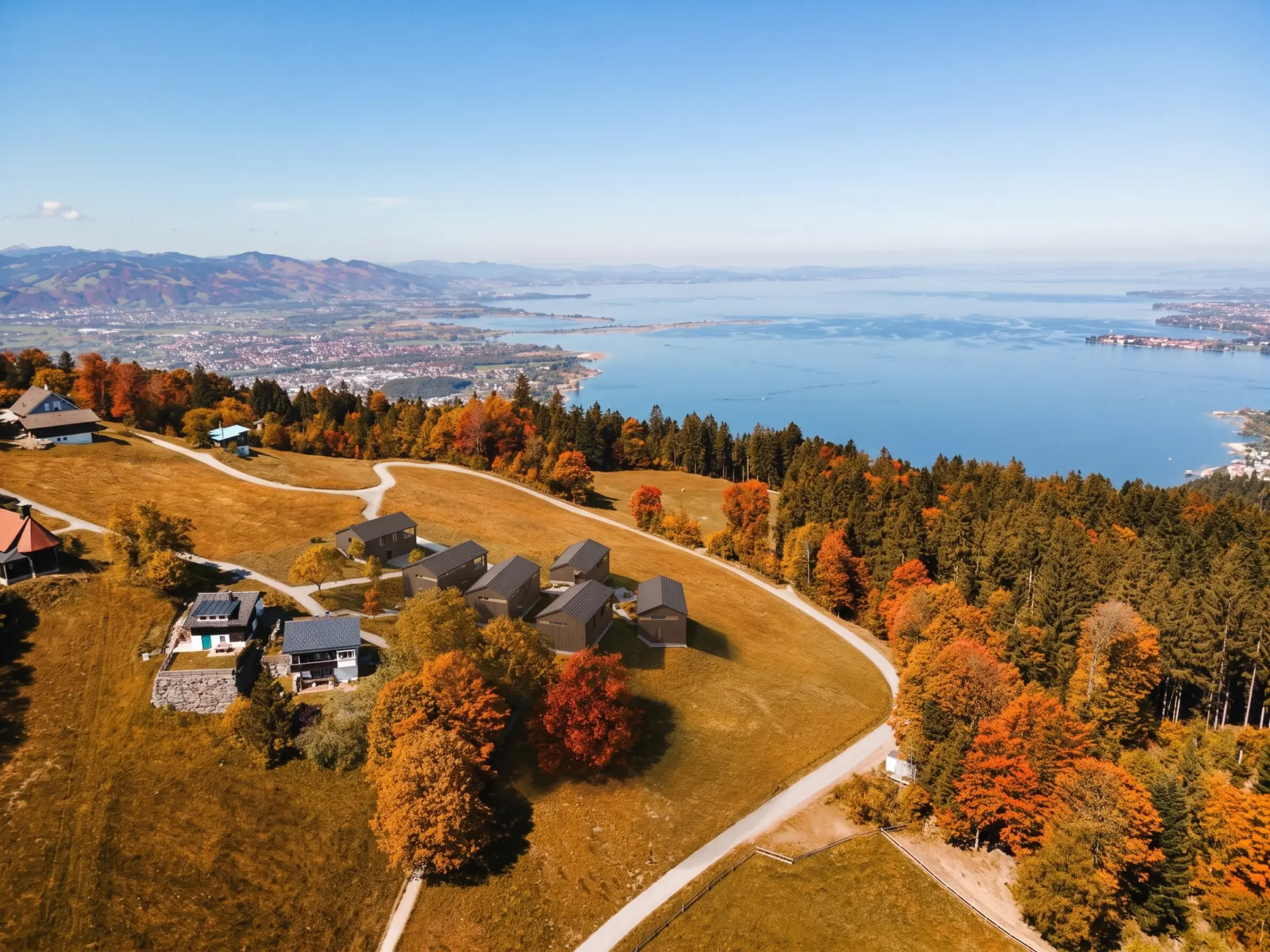 Visualisierung: die sechs Chalets am Pfänder im Herbst, dahinter der Bodensee