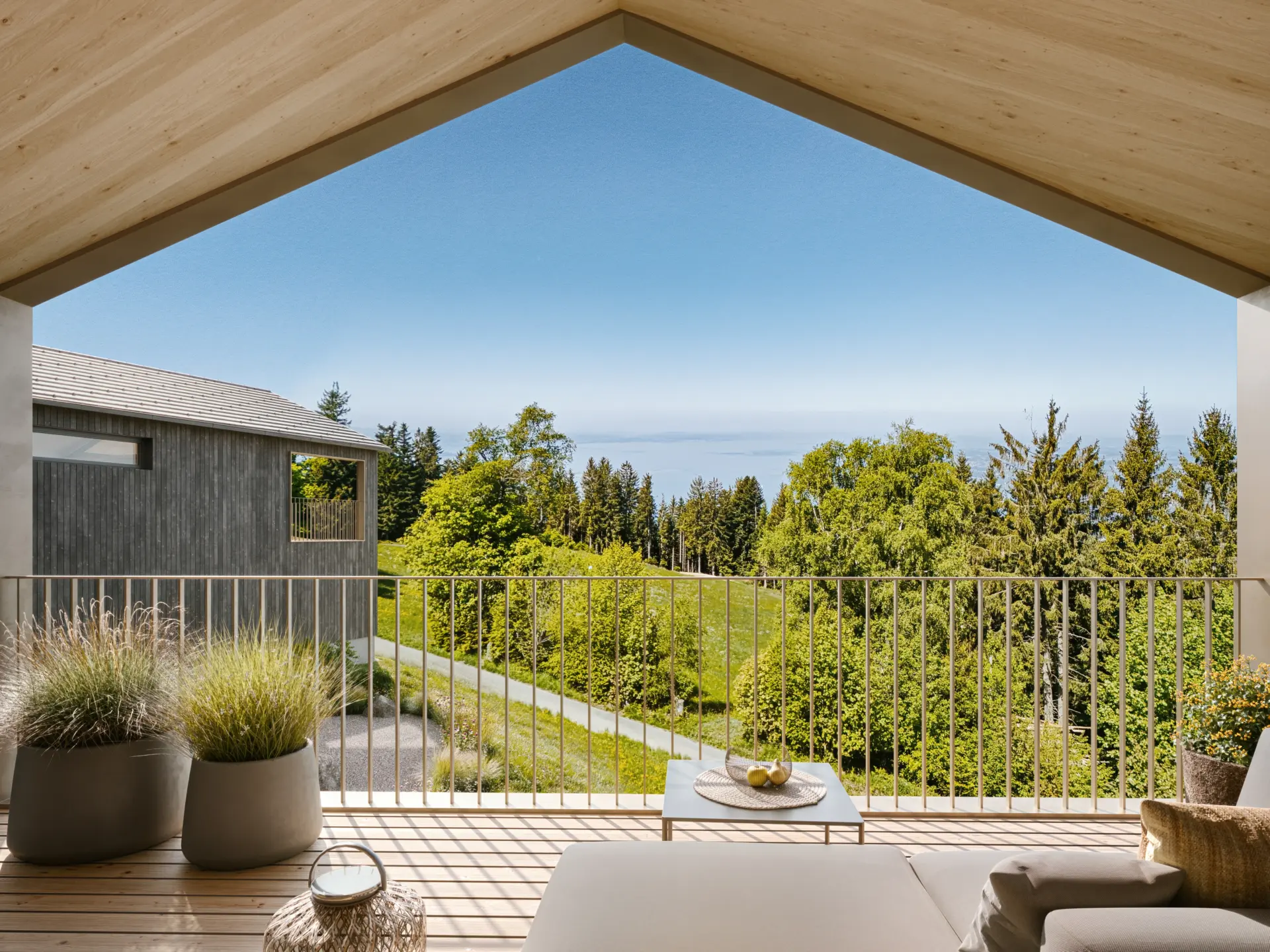 Visualisierung: Loggia mit Lounge und Blick über die Wiesen zum Bodensee im Sommer